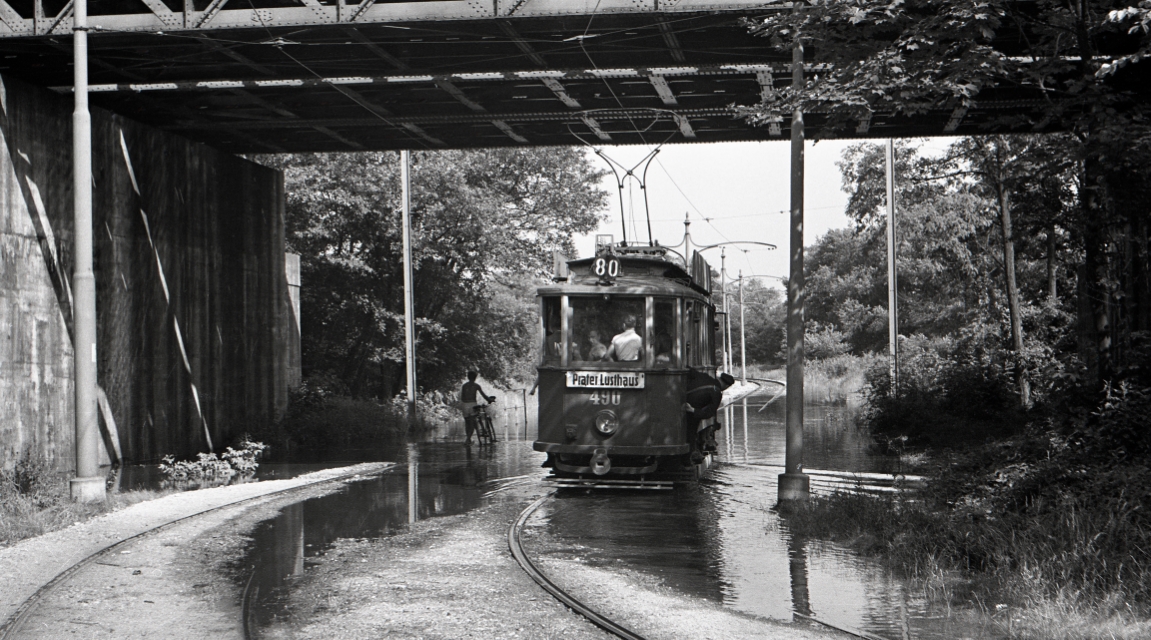Bei der Ostbahnbrücke fährt Triebwagen 490, der Type G als Linie 80 (1954) bei Hochwasser vorbei