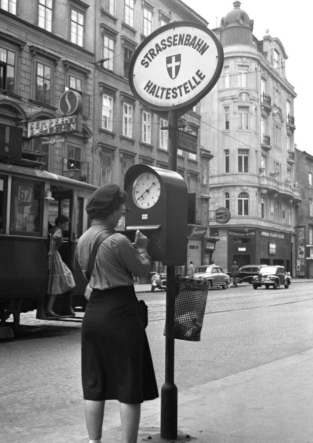 Schaffnerin  beim markieren an der Stechuhr 1959 ,Favoritenstraße, dahinter ein Zug der Linie 67