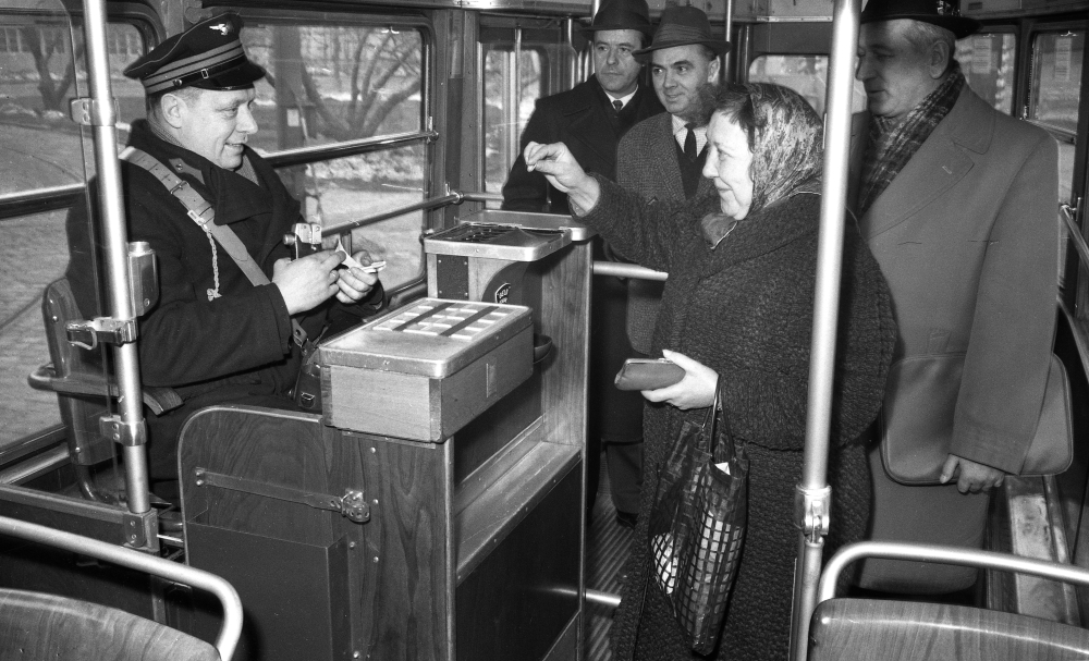 Schaffner  beim Markieren der Fahrscheine für Fahrgäste in einem Zug der Type E, April 1965