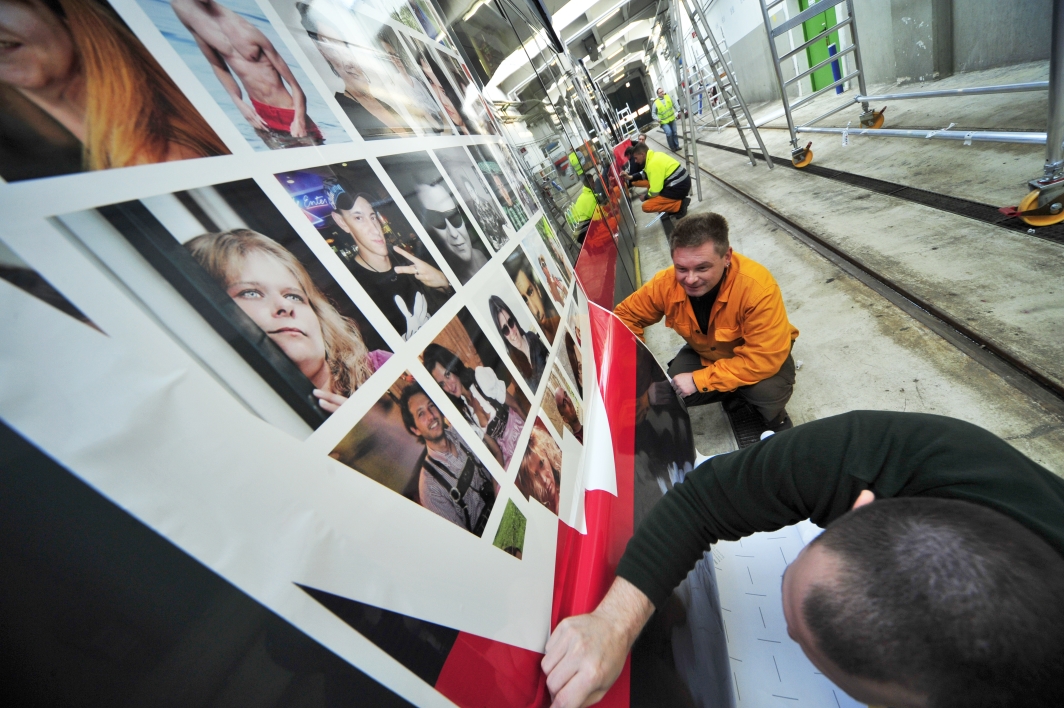 Zwei mit Fotos von Facebook-Freunden der Wiener Linien gestalteten Niederflurstraßenbahn - ULF - werden beklebt.