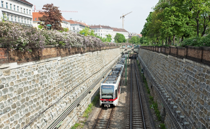 Zug der Linie U6 bei der Burggasse vor blühenden Sträuchern, April14