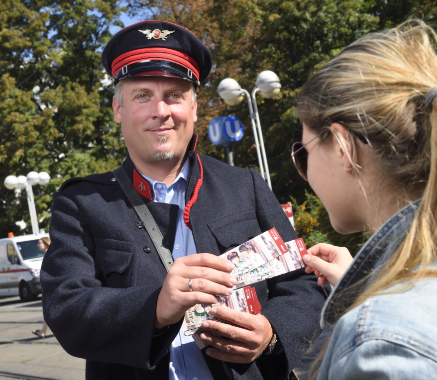 Ein Mitarbeiter der Wiener Linien in historscher Uniform lädt zum Tramwaytag 2016 und verteilt am Reumannplatz Gratisfahrscheine für den 10. September.