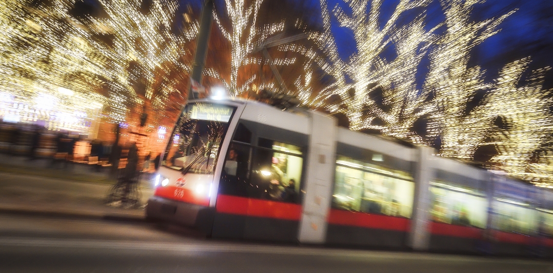 Fahrzeuge der Wiener Linien im weihnachtlich beleuchteten Wien. Hier eine Straßenbahn vor dem Rathausplatz.