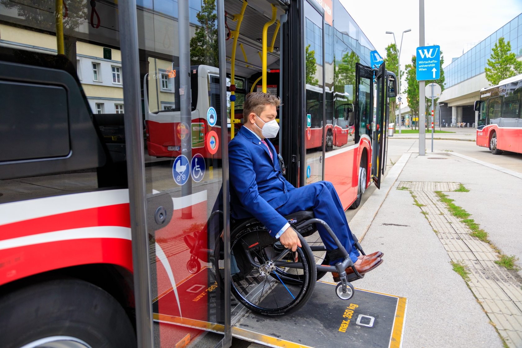 Ein Fahrgast im Rollstuhl nutzt die ausklappbare Rampe, um aus einem Bus auszusteigen.