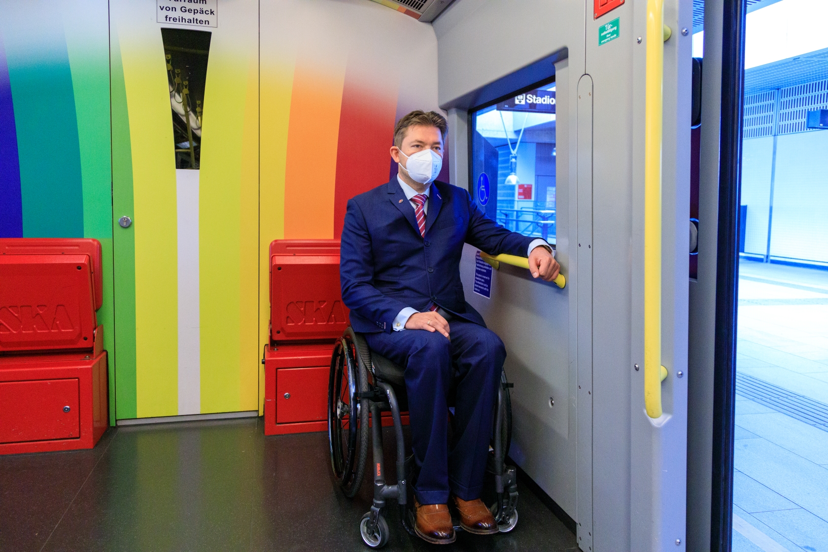 Ein Fahrgast im Rollstuhl steht am Platz für Rollstuhlbenutzer*innen in einer U-Bahn.